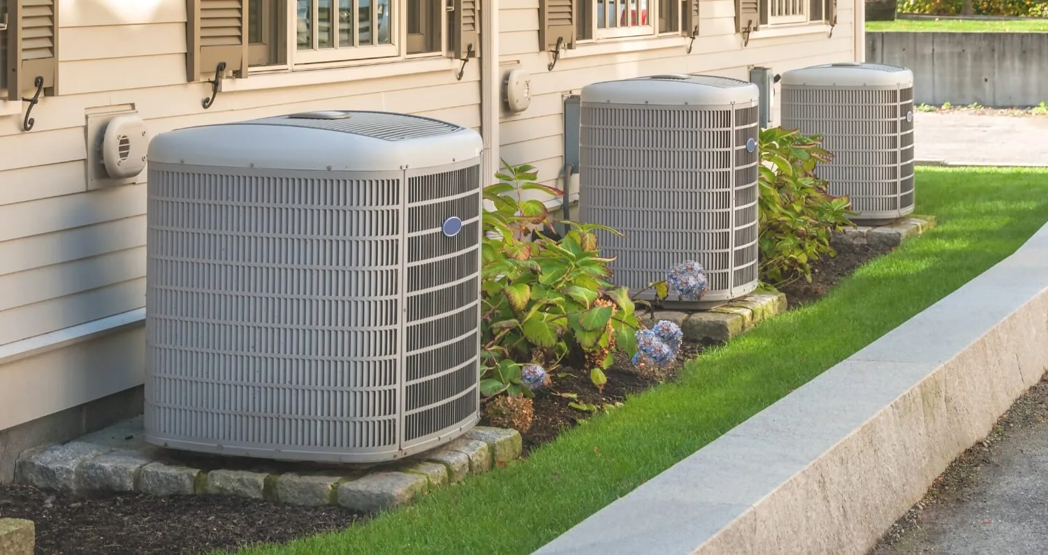 Three separate HVAC systems sit outside of a building.