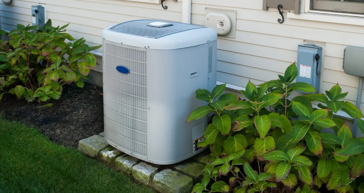 An air conditioning unit sits outside of a house.